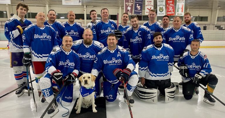 Hockey team posing with a yellow Labrador retriever wearing a BluePath Service Dog vest