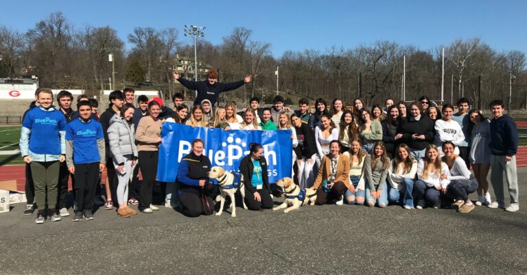 Group of students pose with two yellow labrador retrievers